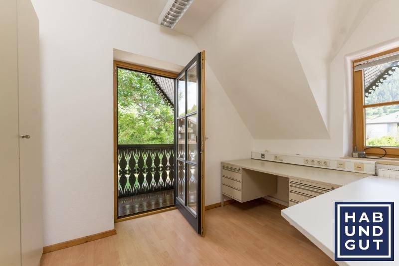 Helles Zimmer mit Schreibtisch und direktem Zugang zu einem traditionellen Holzbalkon.