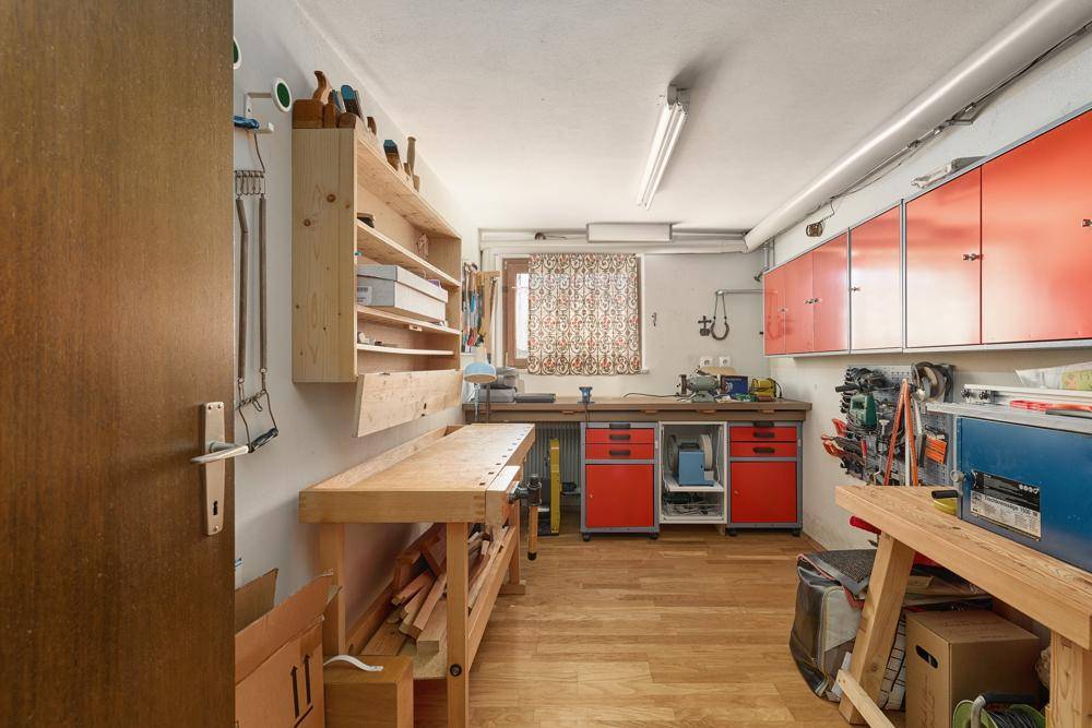 Geräumige Werkstatt mit Holzwerkbank, roten Schränken und viel Stauraum für Werkzeuge.