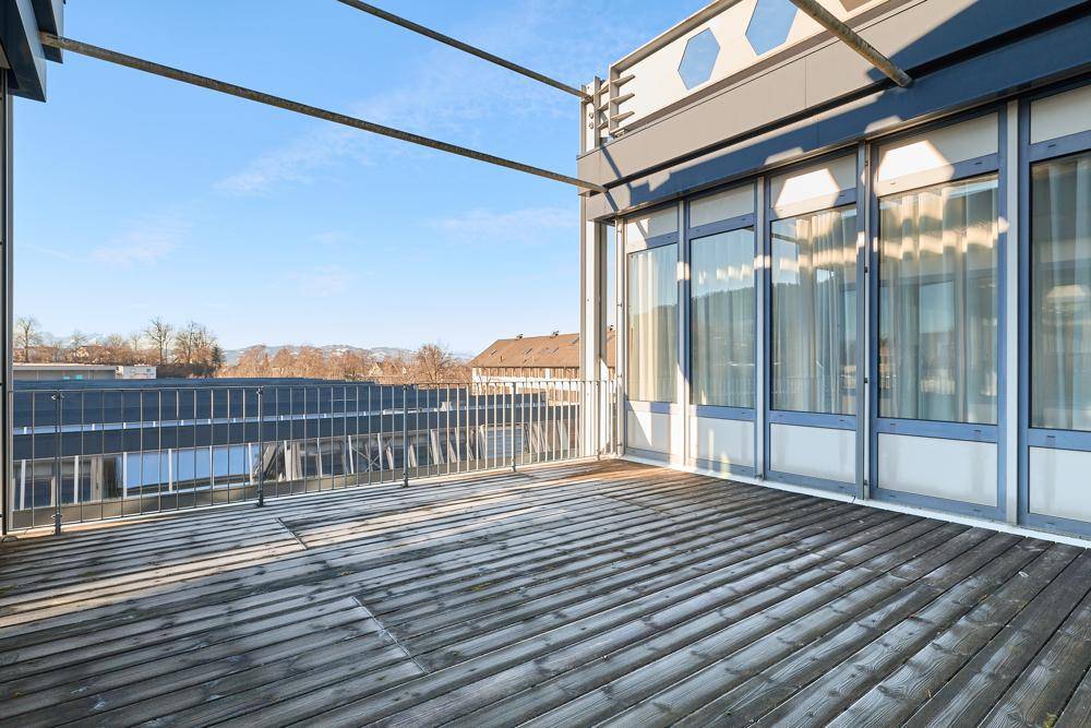Große Dachterrasse mit Holzboden, Metallgeländer und weitem Blick auf die Umgebung.