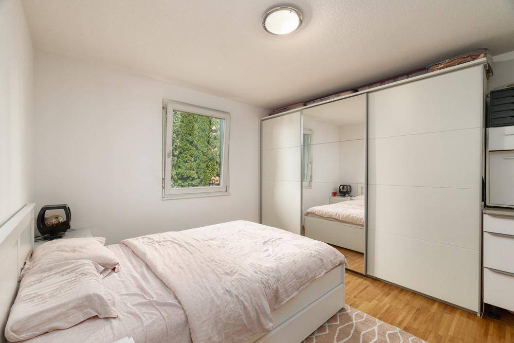 Schlafzimmer mit Doppelbett, Spiegelschrank und Blick ins Grüne.