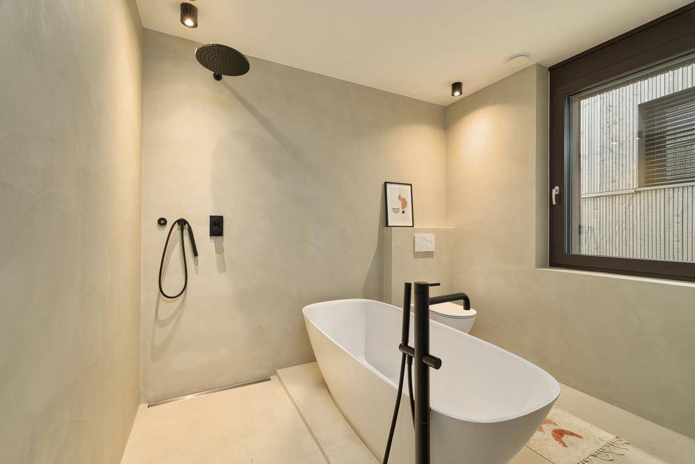 Modernes Badezimmer mit freistehender Badewanne, Regendusche und großem Fenster.