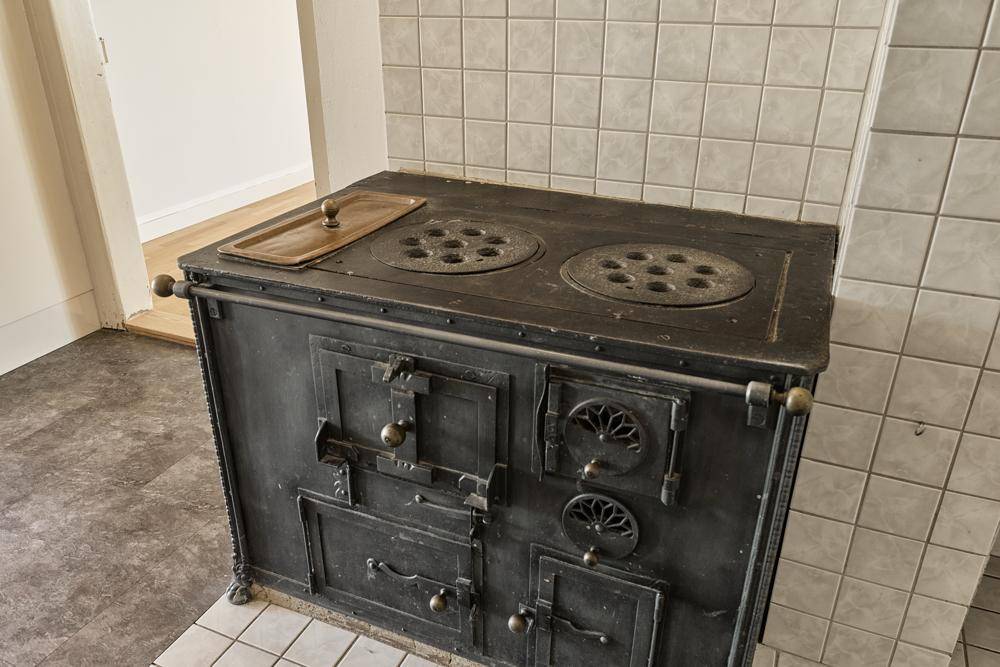 Detailansicht eines traditionellen, gusseisernen Holzofens in der Küche.