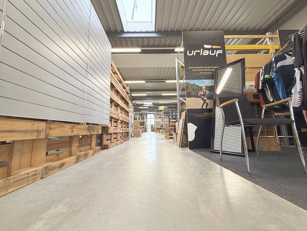 Langer Gang in der Lagerhalle mit Regalen, Auslagen und einem Oberlicht für zusätzliche Helligkeit.