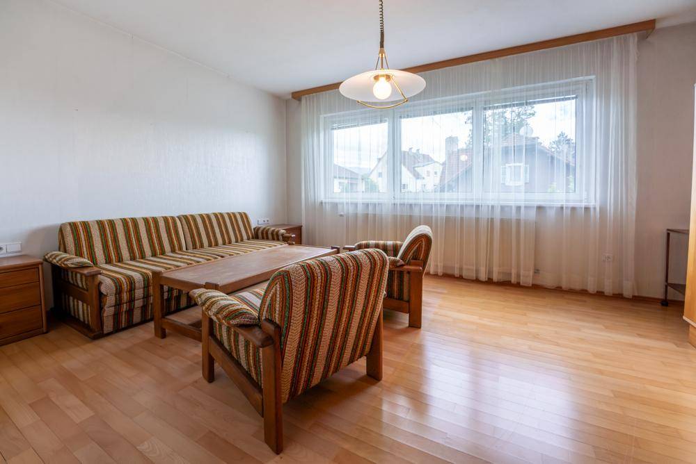 Helles Wohnzimmer mit Holzfußboden, gestreiften Sofas und großem Fenster.