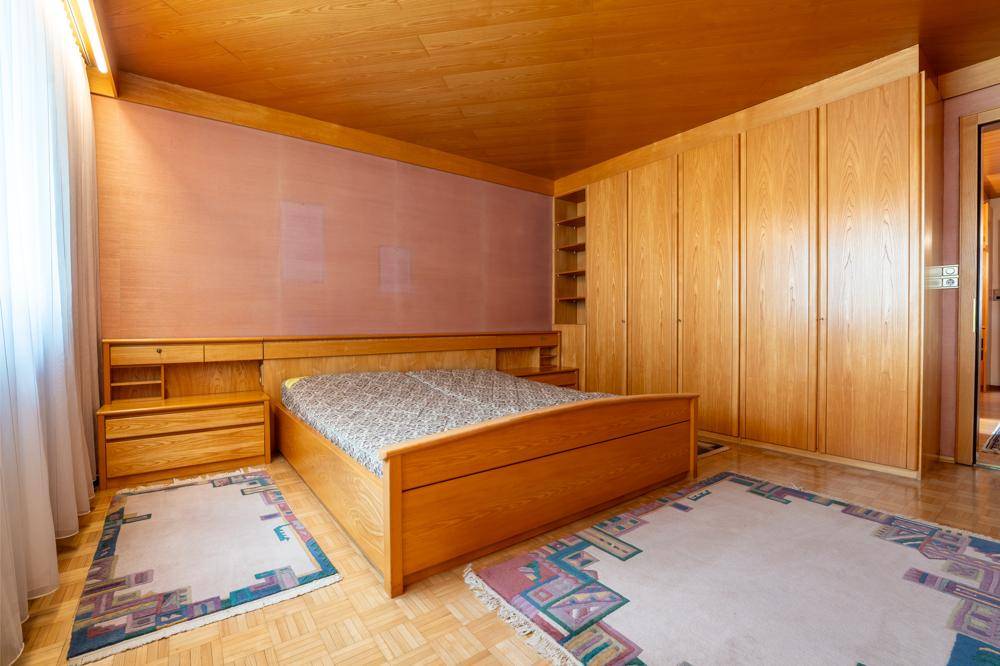 Schlafzimmer mit Holzeinbauschränken, Holzdecke und großem Bett.