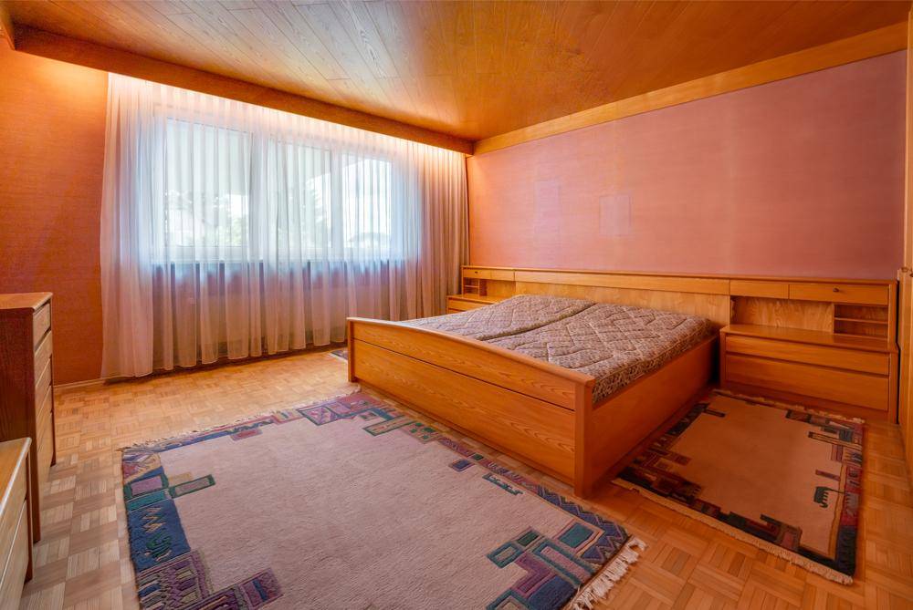 Schlafzimmer mit Holzdecke, Parkettboden und großem Bett mit Nachttischen.