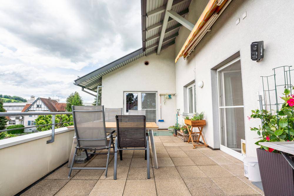 Dachterrasse mit Esstisch, Stühlen und Zugang zum Innenbereich.
