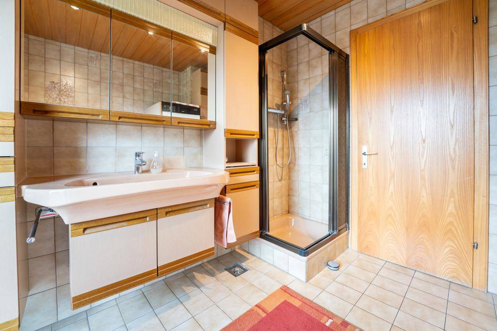 Badezimmer mit Duschkabine, Waschbecken und Holzdecke.