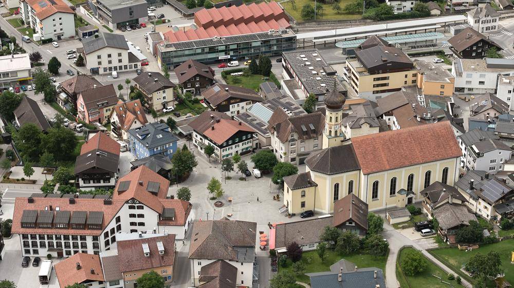Nahaufnahme aus der Luft eines Stadtzentrums mit traditionellen Gebäuden, einer Kirche und einem Marktplatz.