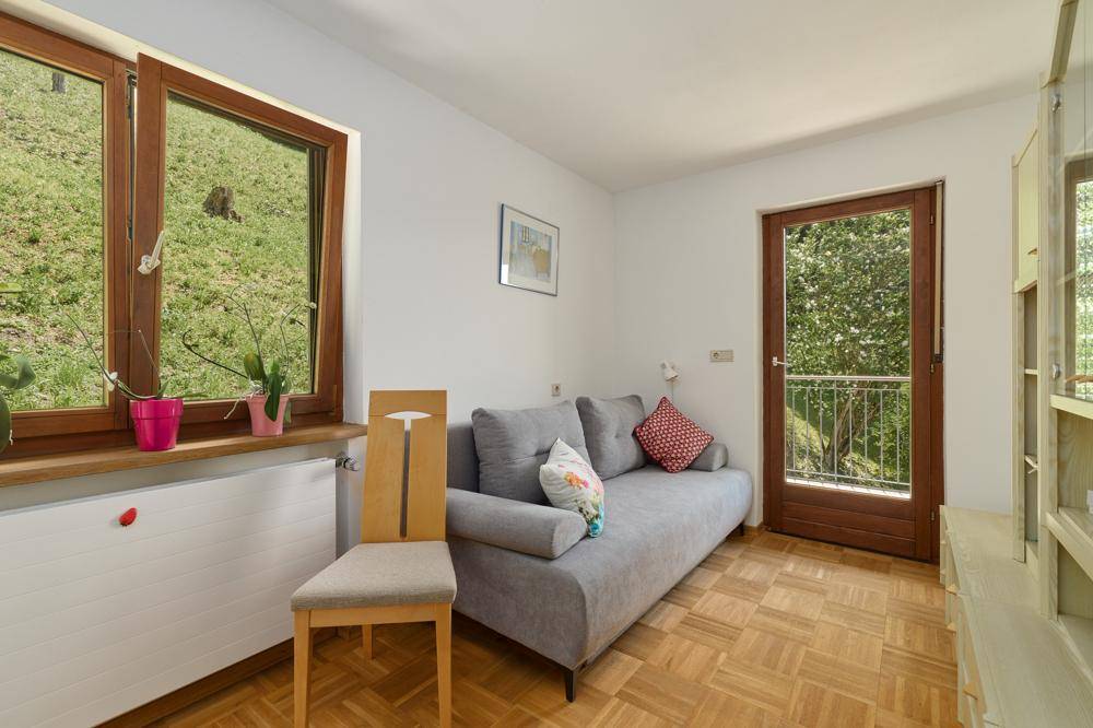 Kleines Schlafzimmer mit Parkettboden, Fenster zum Garten und französischem Balkon.