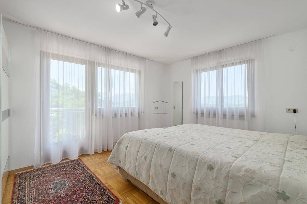 Helles Schlafzimmer mit Parkettboden, großen Fenstern und Zugang zum Balkon.