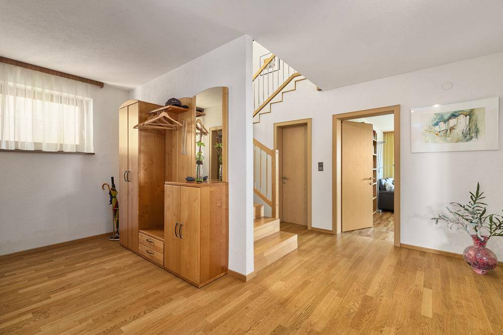 Heller Eingangsbereich mit Holzparkett, Garderobe und Treppe zum Obergeschoss.