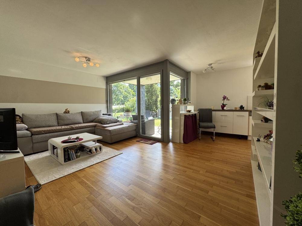 Geräumiger Wohnbereich mit großem Sofa, Holzboden und Zugang zur Terrasse durch eine breite Glasfront.