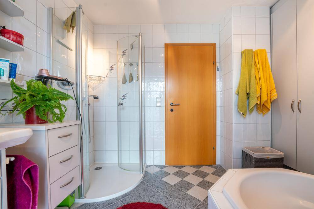 Badezimmer mit Duschkabine, Waschbecken und Stauraum.