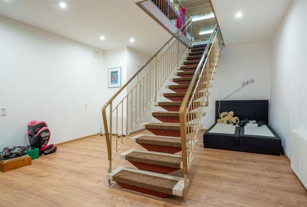 Kellerraum mit Laminatboden, Treppe und zusätzlichem Schlafbereich.