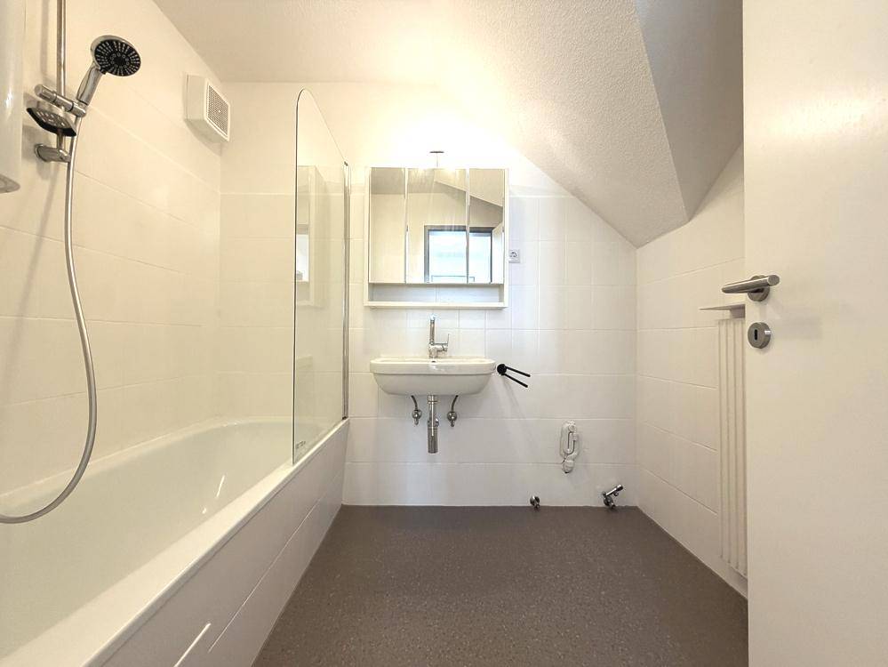 Modernes Badezimmer mit Badewanne, Dusche und Spiegelschrank unter der Dachschräge.