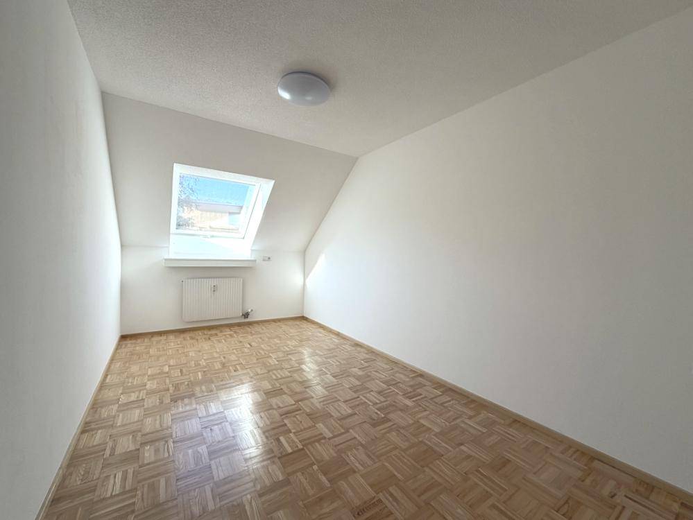 Helles Zimmer mit Dachschräge, Dachfenster und Fischgrätparkett, ideal als Schlaf- oder Arbeitszimmer.