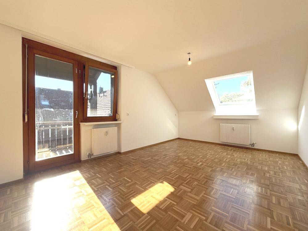 Sonniges Wohnzimmer mit Parkettboden, Dachschräge und direktem Zugang zum Balkon.