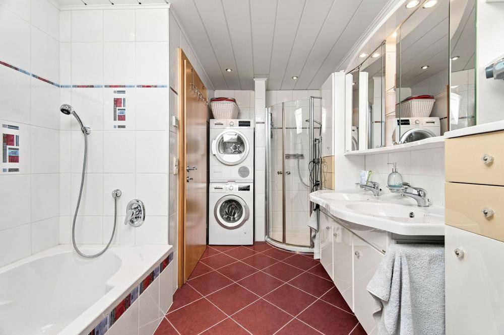 Badezimmer mit Badewanne, Dusche, Doppelwaschbecken und Waschmaschinen-Turm.