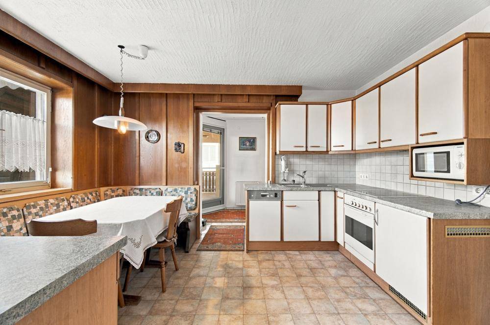 Rustikale Küche mit Holzwänden, Essbereich und integrierten Geräten.