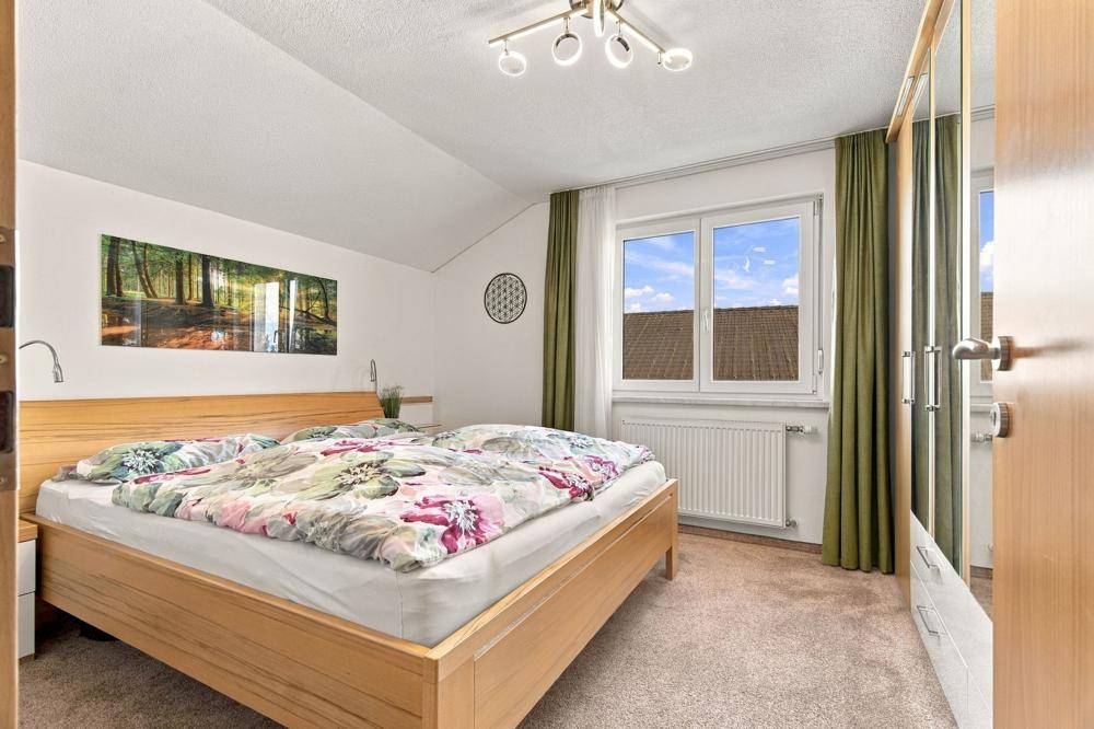 Gemütliches Schlafzimmer mit Doppelbett, Teppichboden und Blick ins Grüne.
