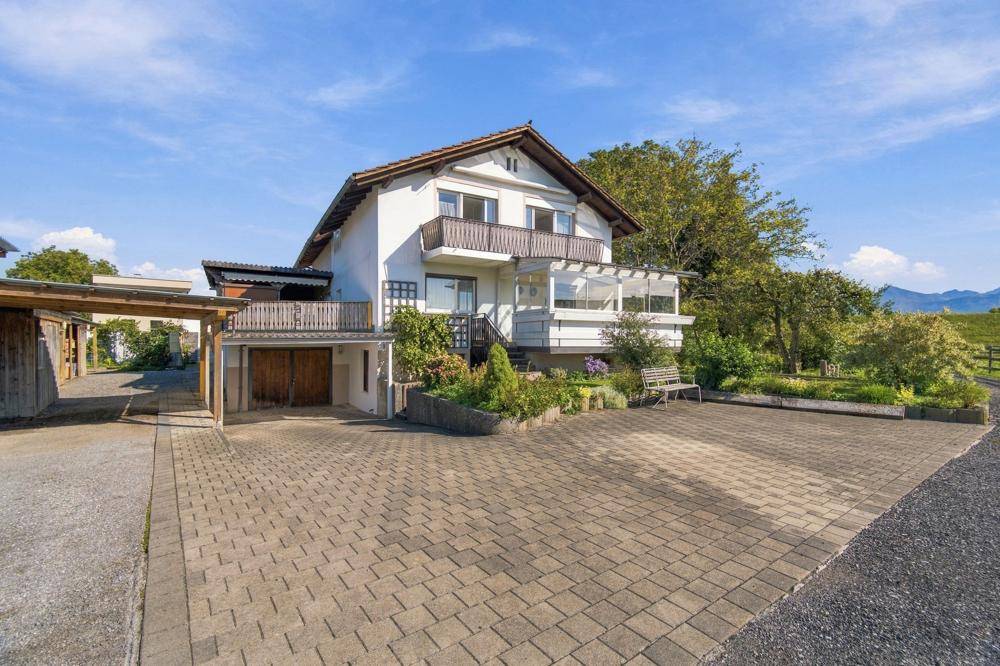 Freistehendes Haus mit gepflasterter Auffahrt, Garage und Gartenbereich.