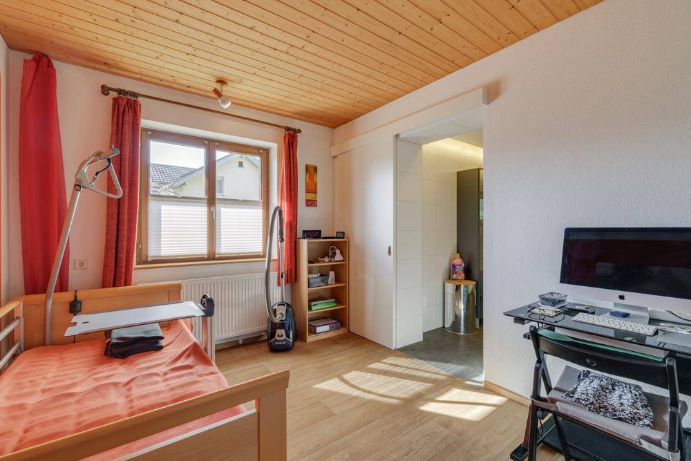 Helles Schlafzimmer mit Holzdecke, Laminatboden und Zugang zu einem angrenzenden Raum.