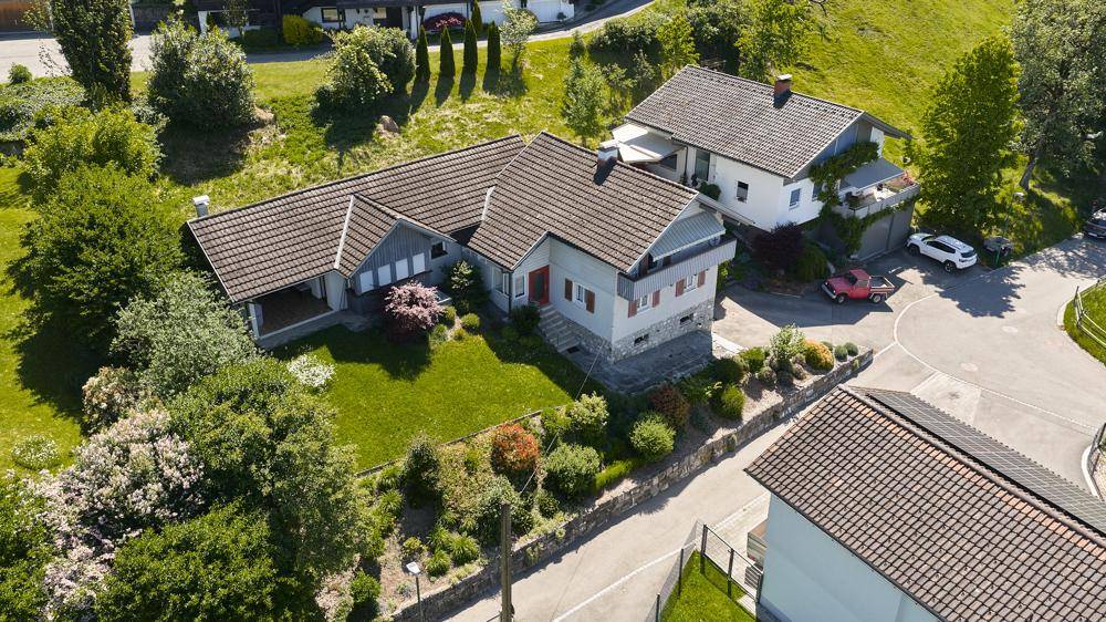 Luftaufnahme des Einfamilienhauses mit großem Garten und umliegender grüner Landschaft.