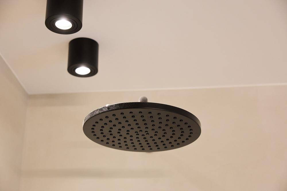 Detailaufnahme einer modernen schwarzen Regendusche mit Deckenstrahlern in einem Badezimmer.