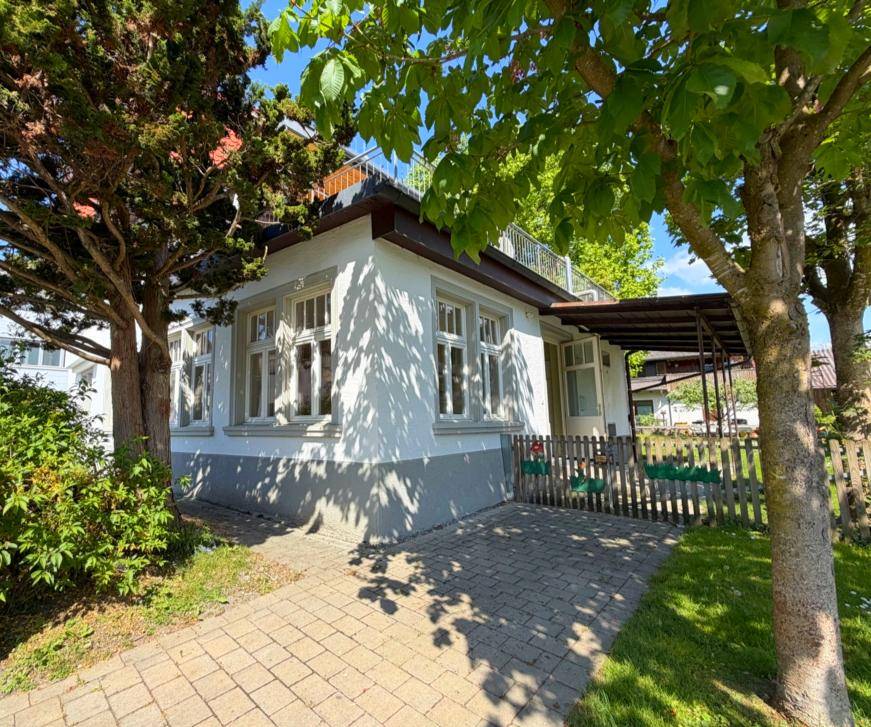 Seitenansicht des Gebäudes mit gepflastertem Weg und Bäumen im Vorgarten.