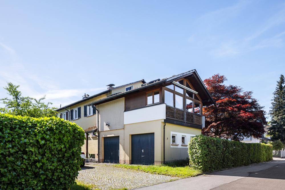Außenansicht des Hauses von der Straße mit Garagen und verglastem Wintergarten.