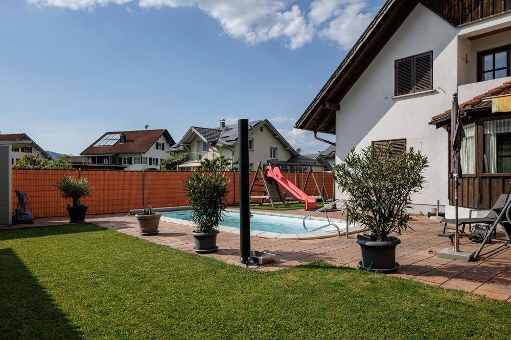 Gepflegter Gartenbereich mit Swimmingpool, Rasenfläche, Kinderrutsche und Sitzgelegenheiten.