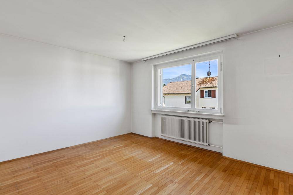 Helles Schlafzimmer mit Parkettboden und weiten Blick auf die umliegenden Berge.