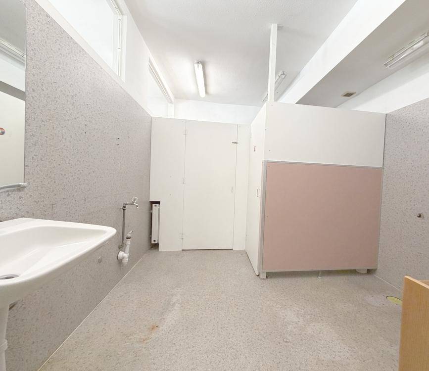 Badezimmer mit Waschbecken und hellen Trennwänden, in gutem Zustand.