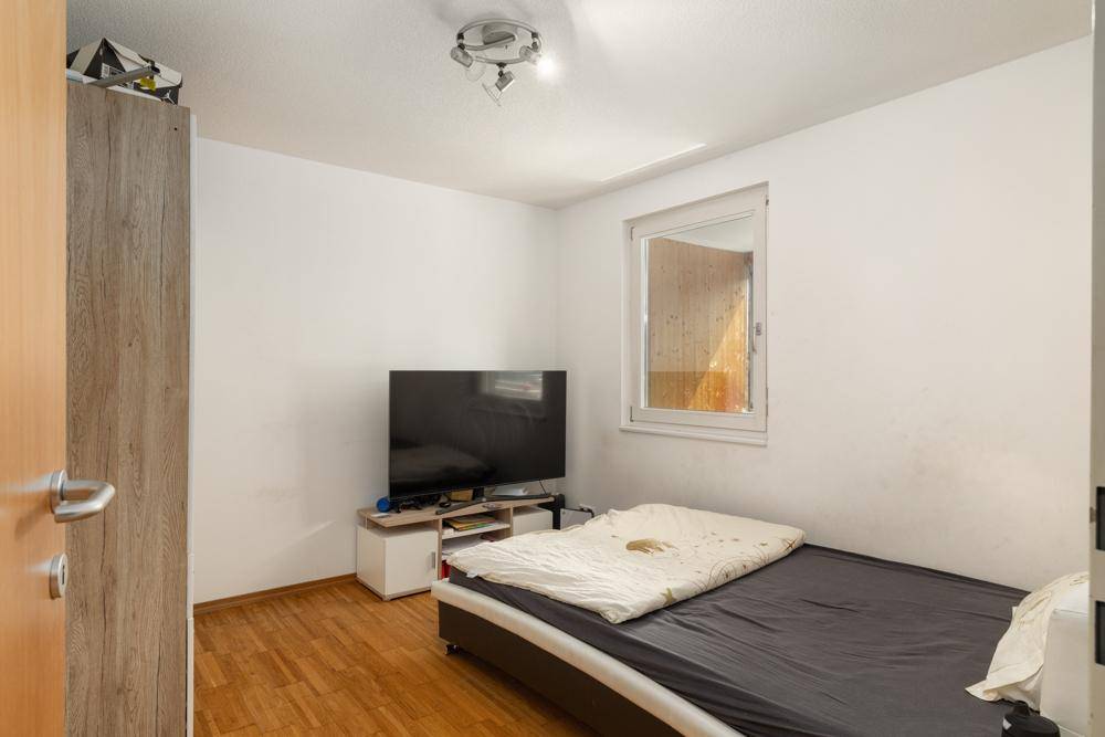 Kinderzimmer mit Einzelbett, Fernseher und Holzboden.
