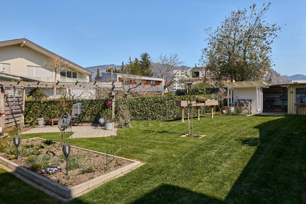 Großer, gepflegter Garten mit Rasenfläche, Blumenbeeten und Gartenhaus.