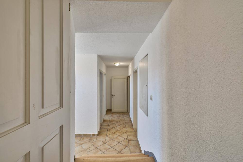 Langer, heller Flur mit Fliesenboden und mehreren Türen zu angrenzenden Räumen.