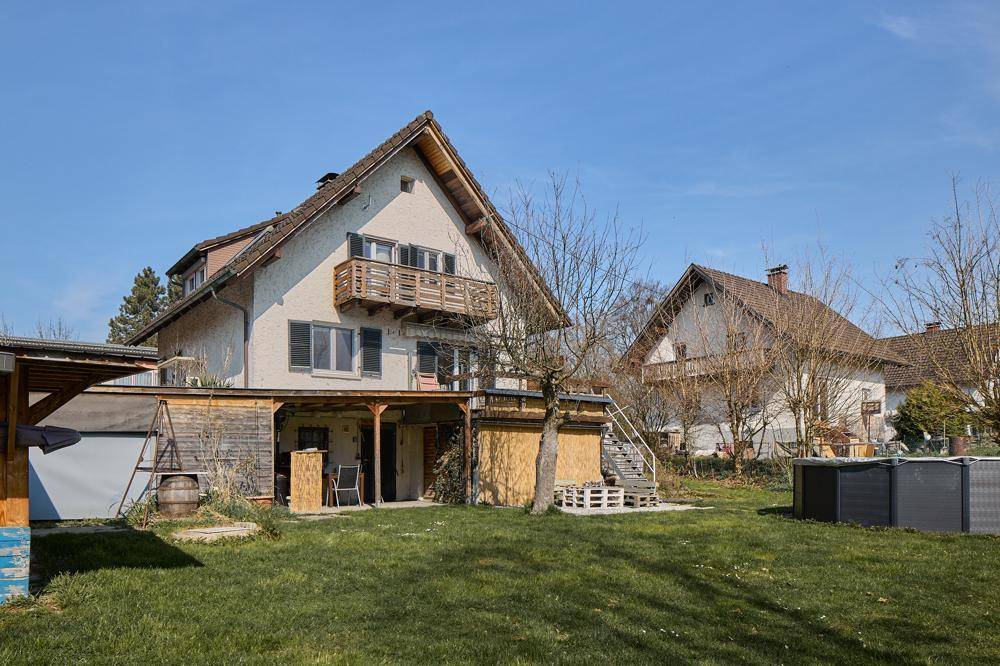 Hinteransicht des Hauses mit großem Garten, Rasenfläche und einem kleinen Aufstellpool.