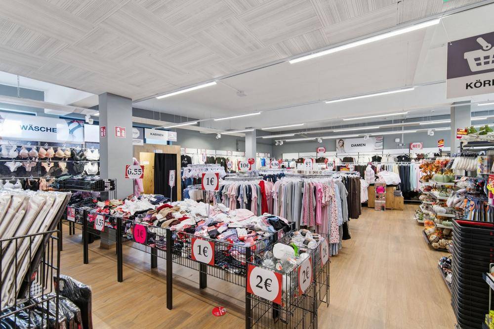 Innenansicht des Woolworth-Geschäfts mit zahlreichen Kleiderständern und Warenpräsentationen.