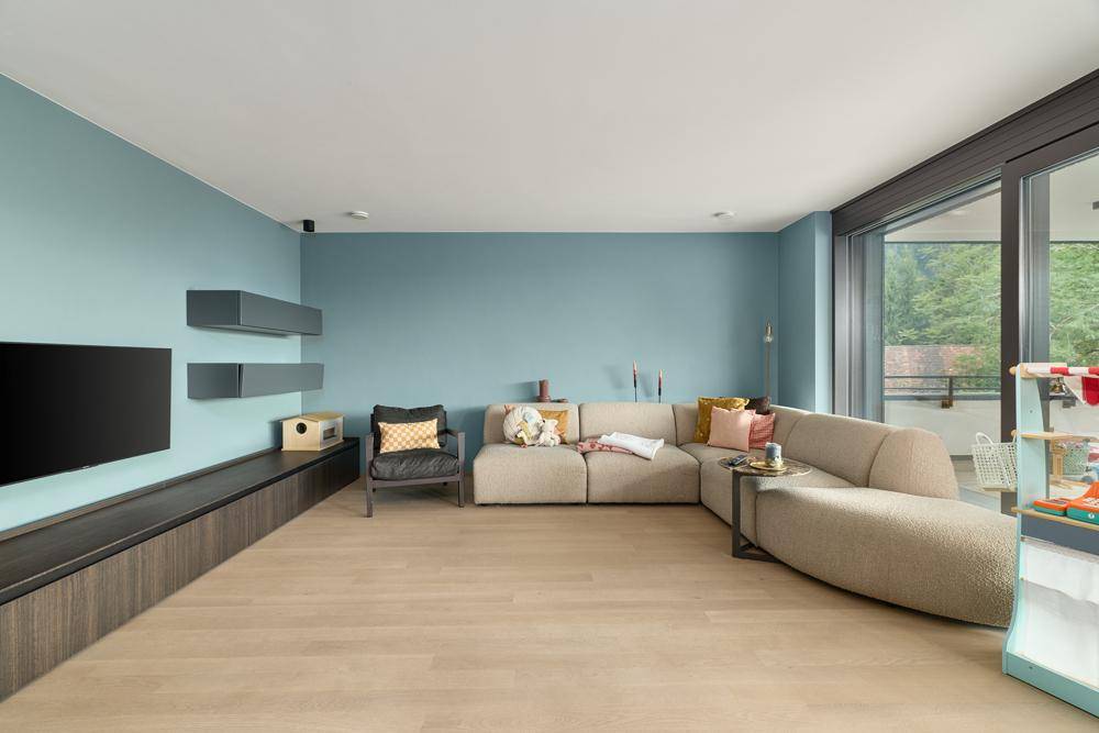 Geräumiges Wohnzimmer mit blauen Wänden, Holzboden und großem Sofa.