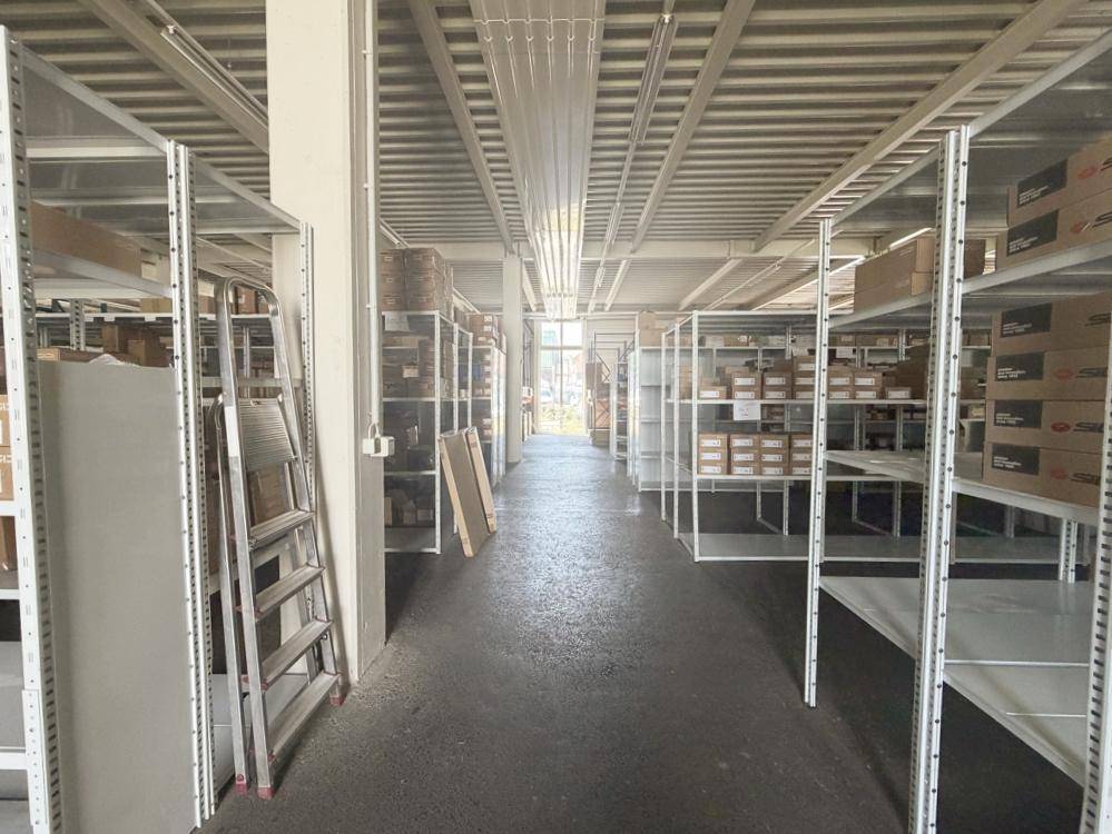 Langer Gang in einer Lagerhalle mit Metallregalen, gefüllt mit Kartons und Produkten.