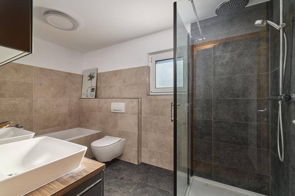 Modernes Badezimmer mit begehbarer Dusche, Badewanne und Fenster.