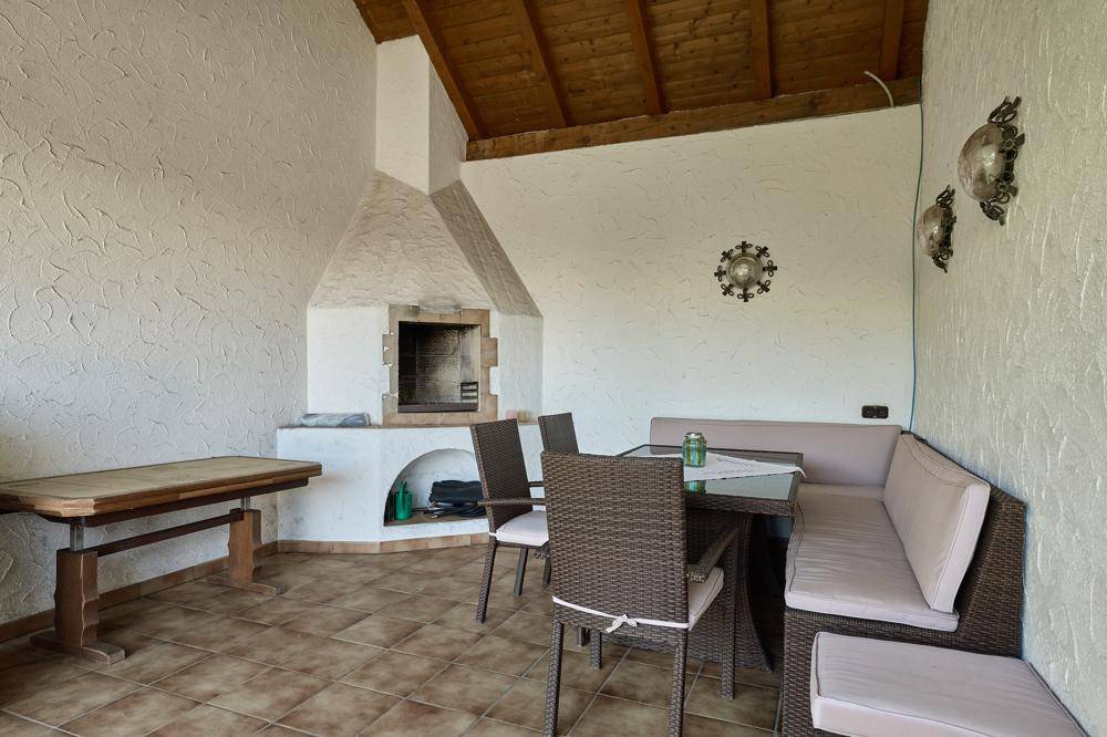Überdachte Terrasse mit gemauertem Grill und gemütlicher Sitzgruppe.