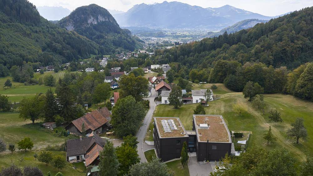 Luftaufnahme einer modernen Wohnanlage in einer grünen, bergigen Landschaft.