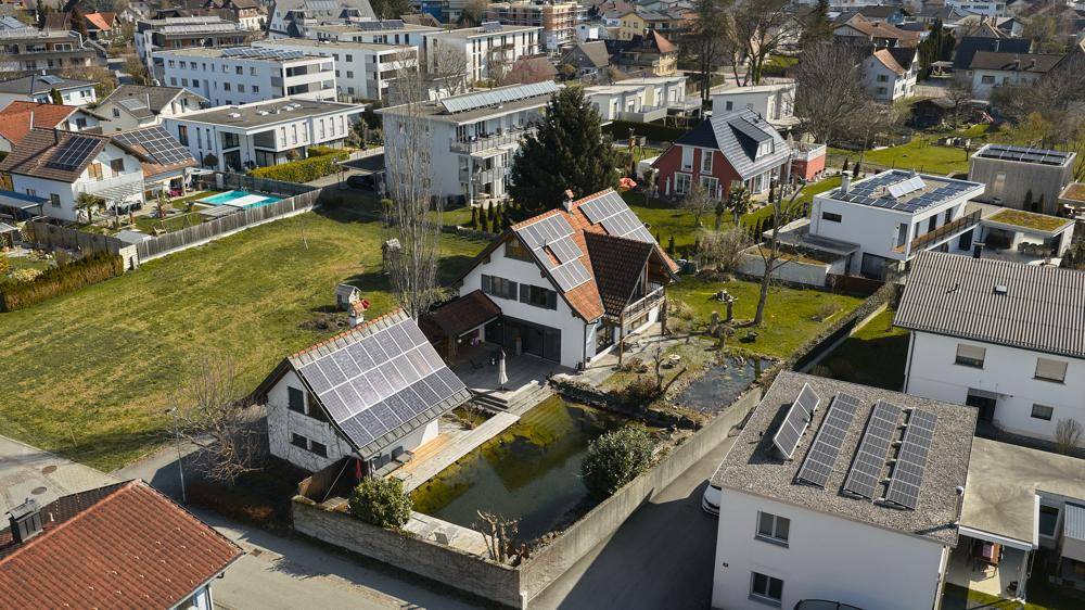 Luftaufnahme des Anwesens mit Solaranlagen, Naturteich und umliegender Bebauung.