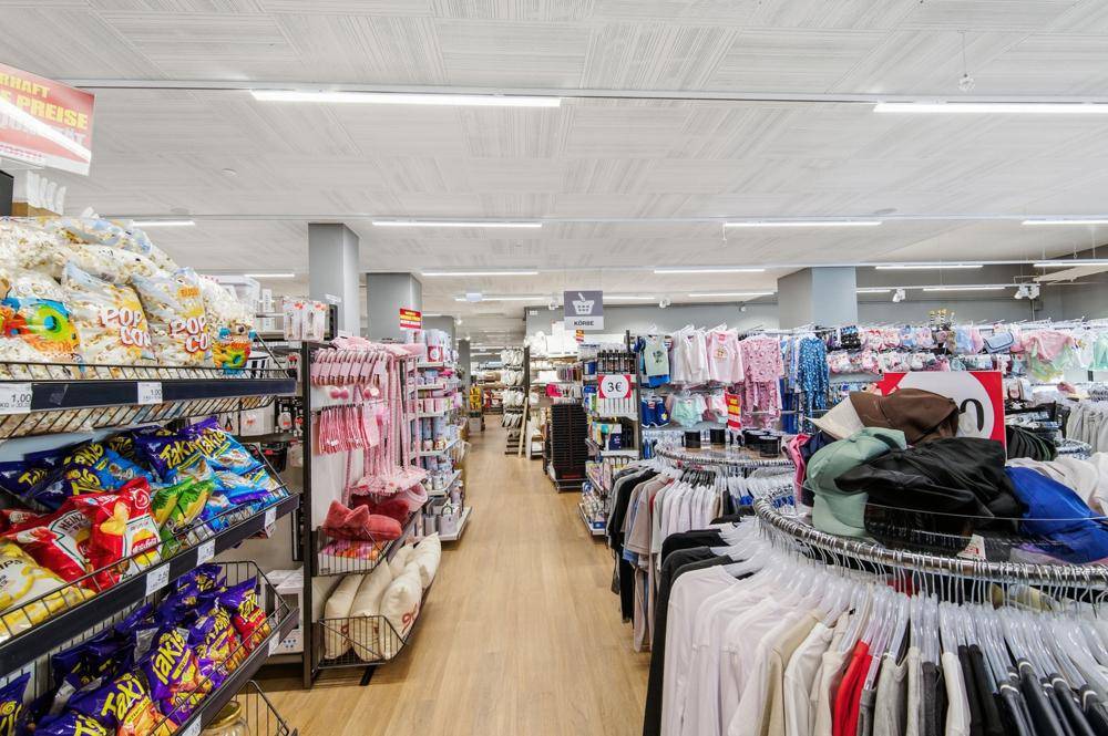 Langer Gang im Woolworth-Geschäft mit Regalen voller Snacks, Kleidung und Haushaltswaren.