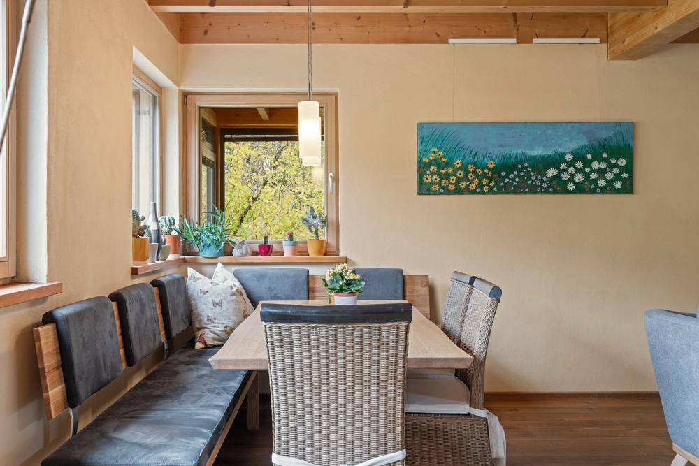 Gemütlicher Essbereich mit Holztisch, Sitzbank und Blick auf die Natur.