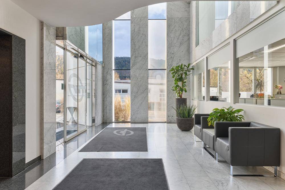Eindrucksvolle moderne Lobby mit hohen Decken, Marmorboden und großen Glasfronten, die viel Licht hereinlassen.