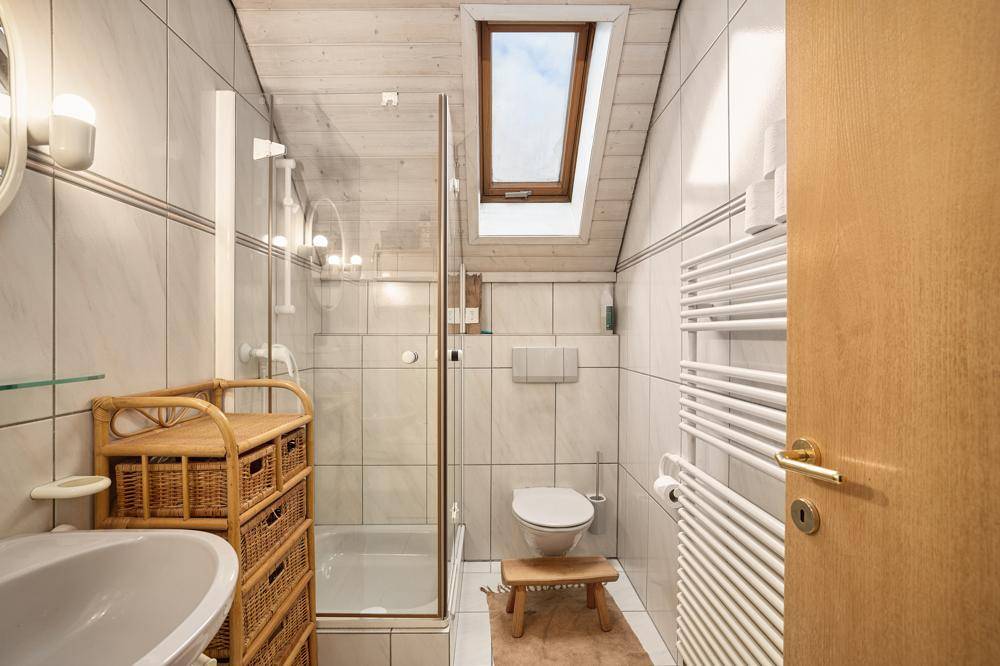 Badezimmer mit Dusche, WC, Handtuchheizkörper und Dachfenster für natürliches Licht.