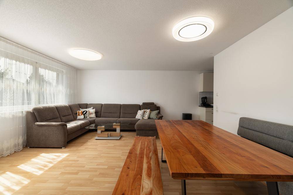 Geräumiger Wohn- und Essbereich mit Holztisch und Blick in die angrenzende Küche.
